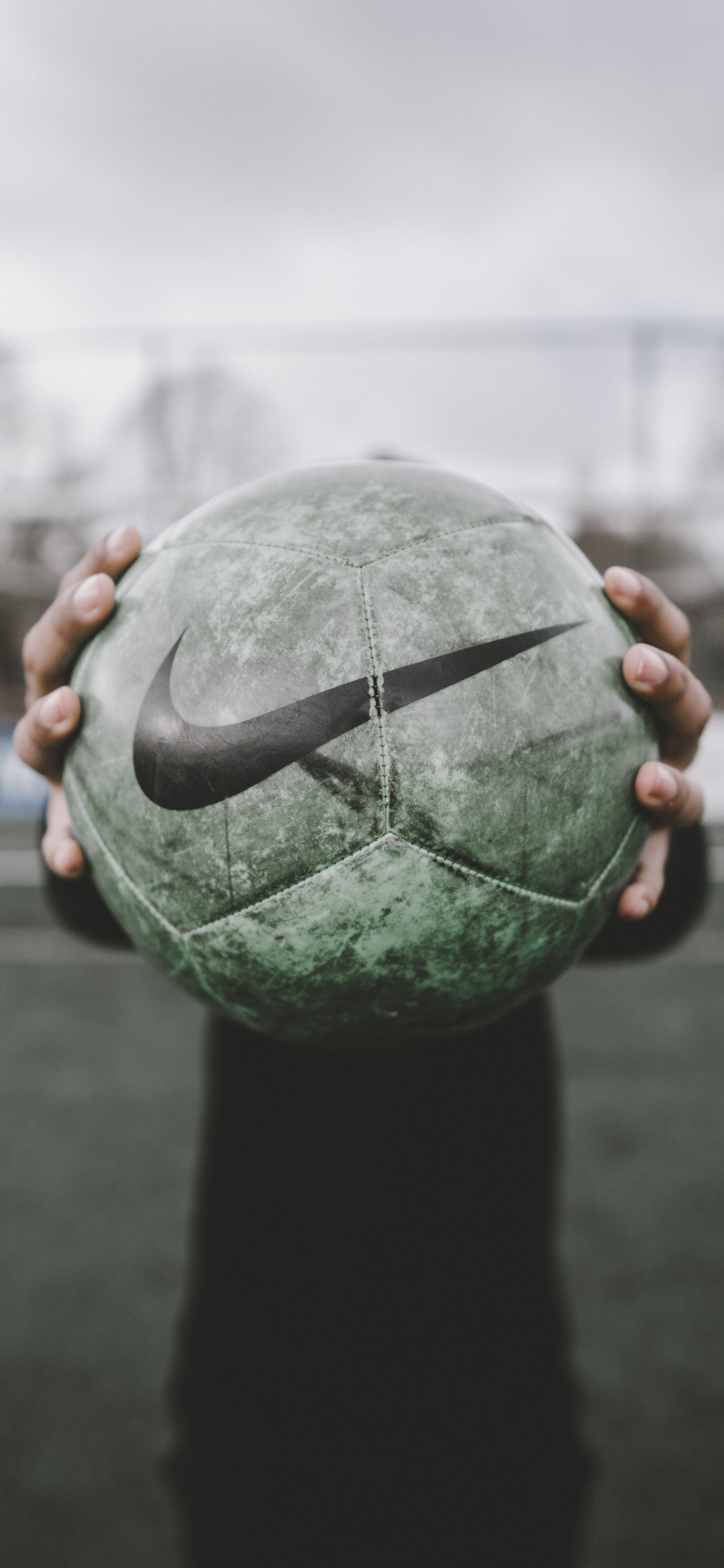 Person Holding Green and Black Ball. Wallpaper in 1125x2436 Resolution