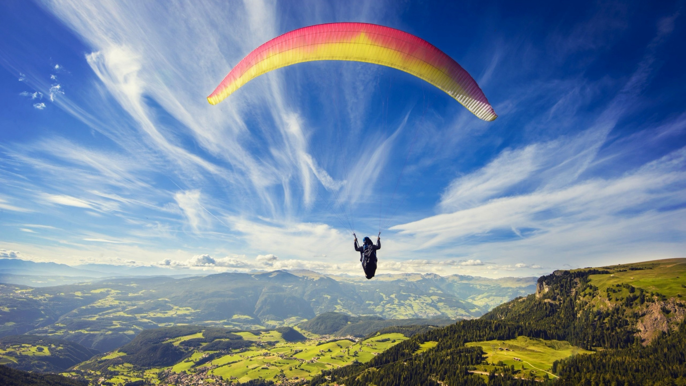 Person in Red and Yellow Parachute Over Green Mountains During Daytime. Wallpaper in 1366x768 Resolution