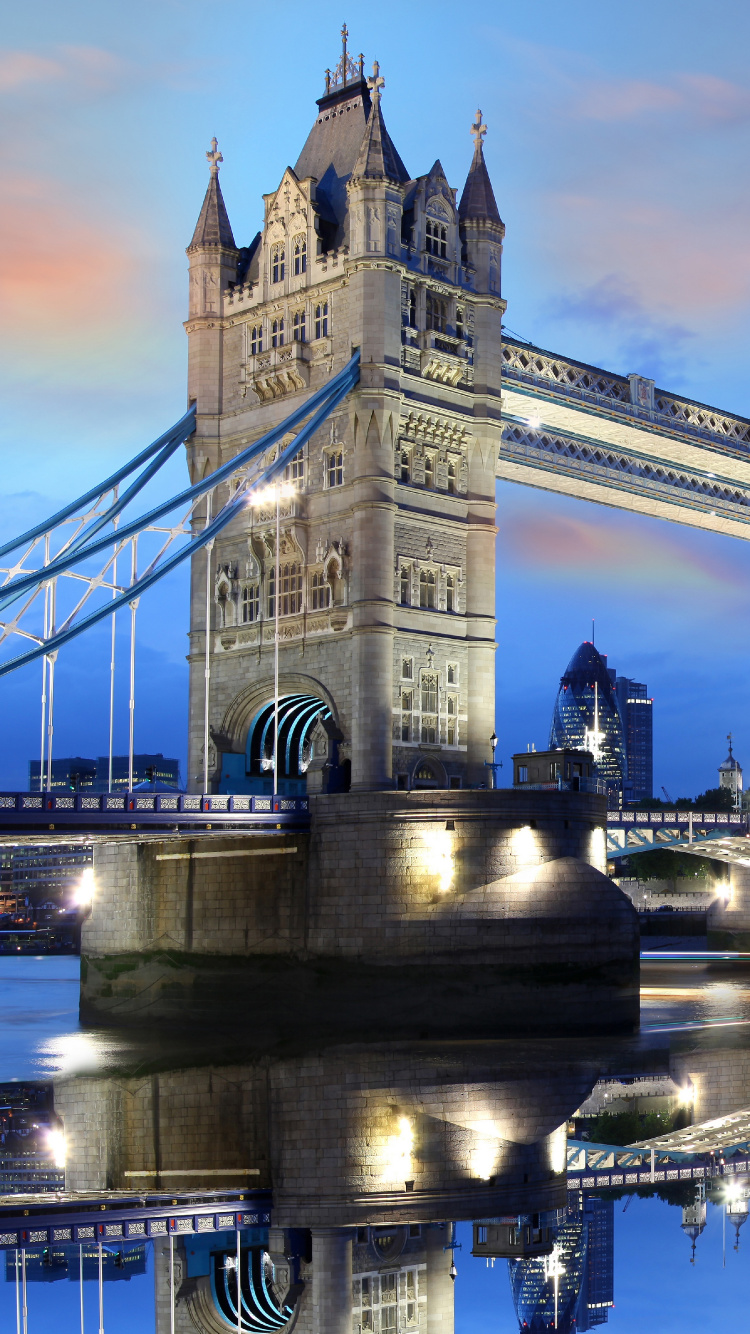 Leute, Die Nachts Auf Der Brücke in Der Nähe Eines Weißen Betongebäudes Gehen. Wallpaper in 750x1334 Resolution