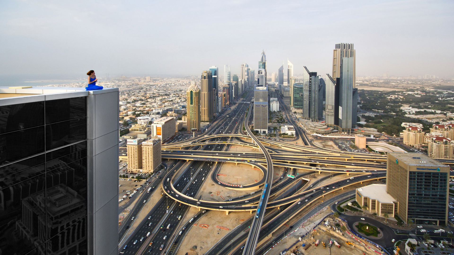 Mann in Blauer Jacke, Der Auf Einem Gebäude Sitzt Und Tagsüber Die Gebäude Der Stadt Betrachtet. Wallpaper in 1920x1080 Resolution