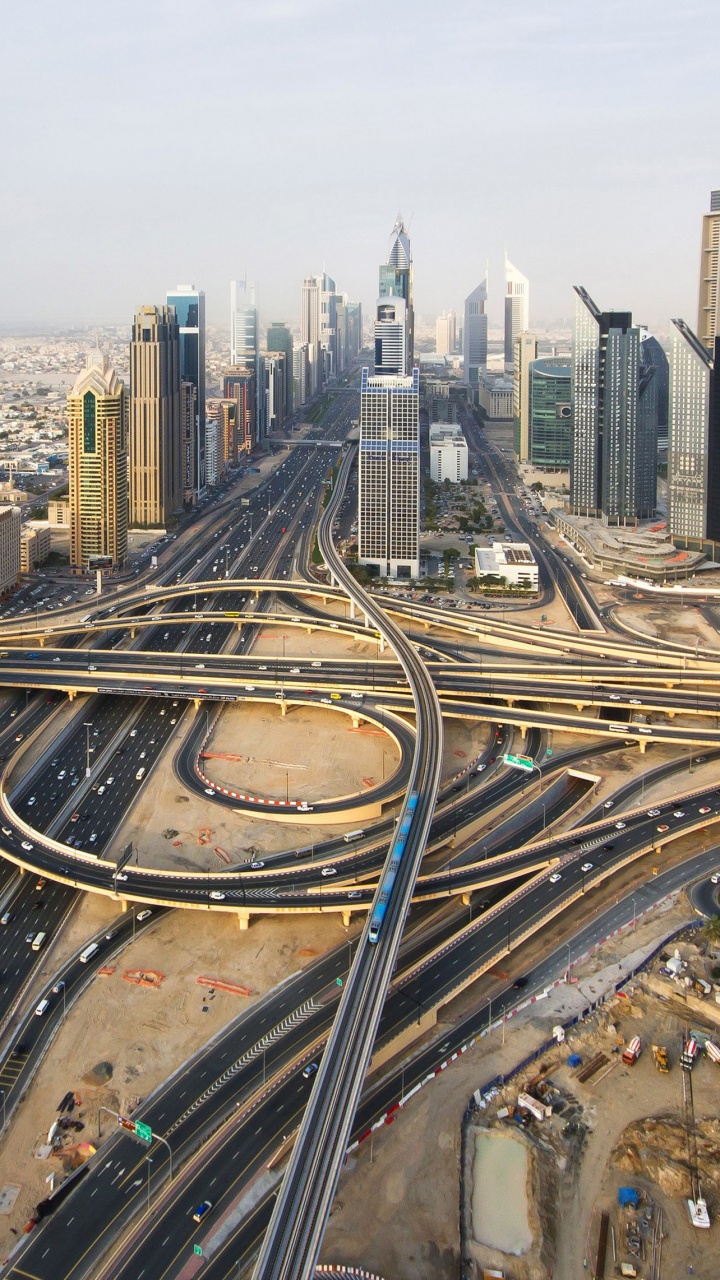 Mann in Blauer Jacke, Der Auf Einem Gebäude Sitzt Und Tagsüber Die Gebäude Der Stadt Betrachtet. Wallpaper in 720x1280 Resolution