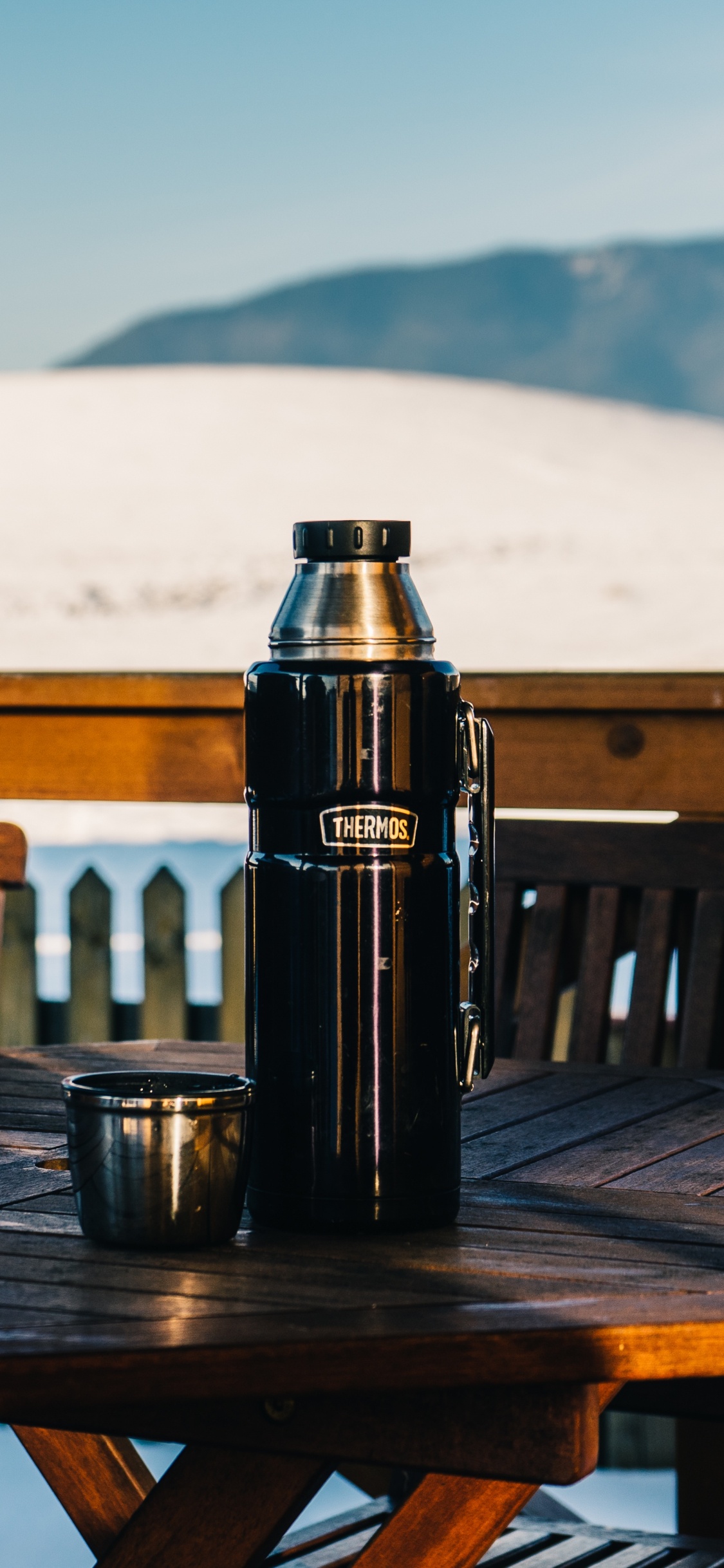 Black Vacuum Flask on Brown Wooden Table. Wallpaper in 1125x2436 Resolution