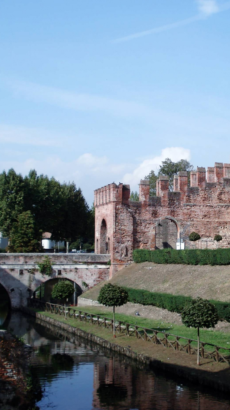 Edificio de Hormigón Marrón Cerca Del Río Bajo un Cielo Azul Durante el Día. Wallpaper in 750x1334 Resolution