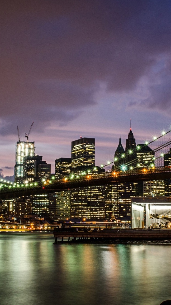 Beleuchtete Brücke Über Den Fluss Während Der Nacht. Wallpaper in 720x1280 Resolution