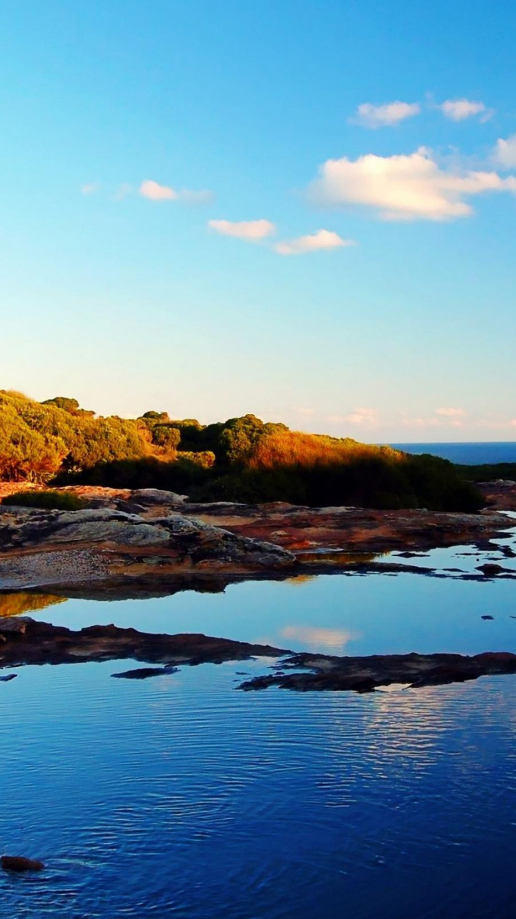 Montaña Marrón y Verde Junto al Cuerpo de Agua Durante el Día.. Wallpaper in 750x1334 Resolution