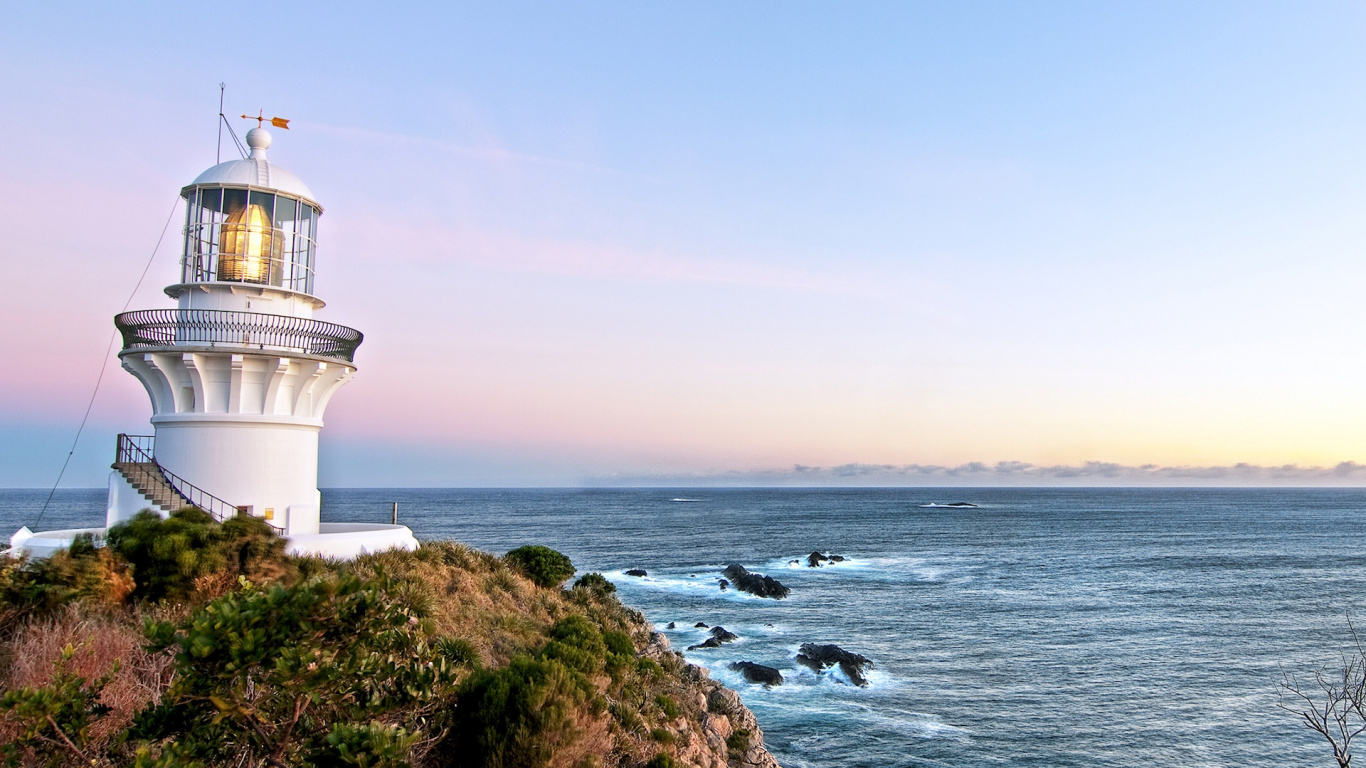White Lighthouse on Brown and Green Grass Field Near Body of Water During Daytime. Wallpaper in 1366x768 Resolution