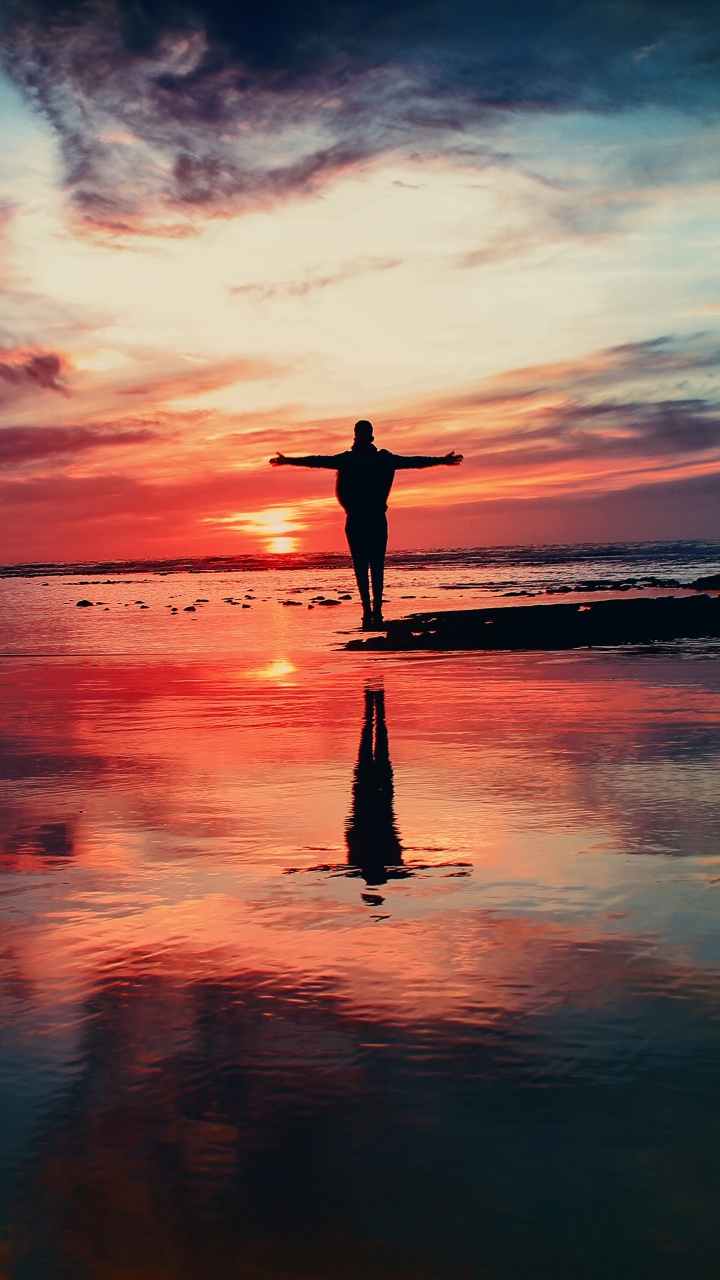 Silhouette of Person Standing on Seashore During Sunset. Wallpaper in 720x1280 Resolution