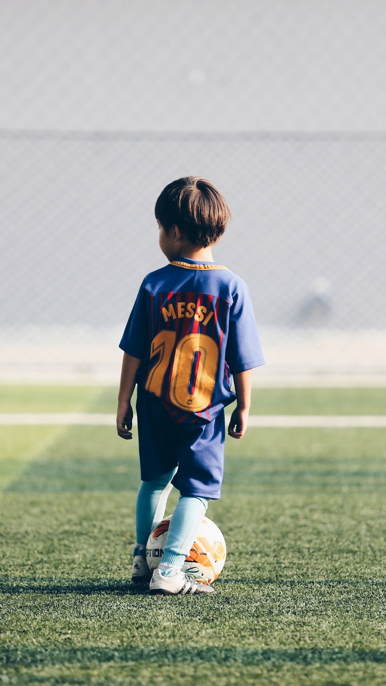 Boy in Blue and Red Soccer Jersey Shirt and White Shorts Running on Green Grass Field. Wallpaper in 750x1334 Resolution