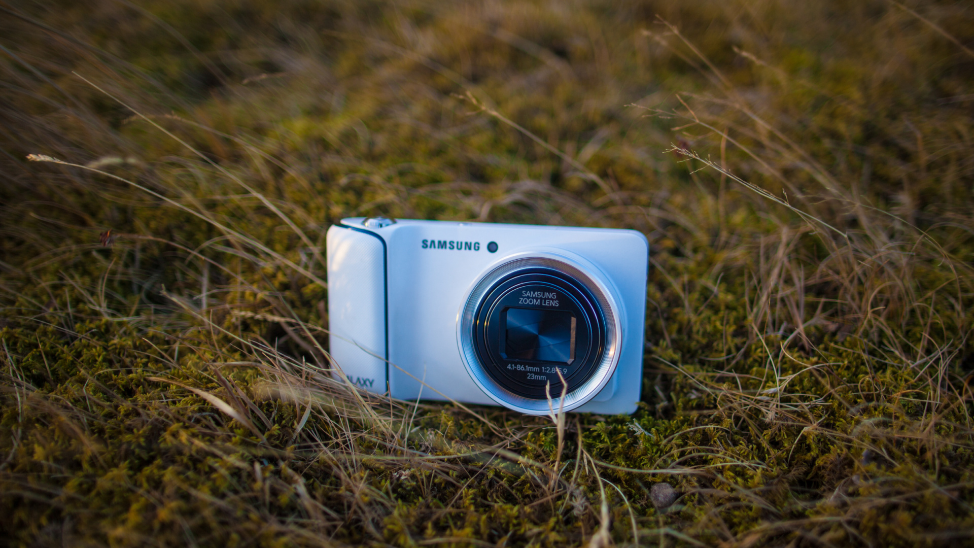 Weißer Samsung Point Und Kamera Auf Braunem Gras Schießen. Wallpaper in 1920x1080 Resolution