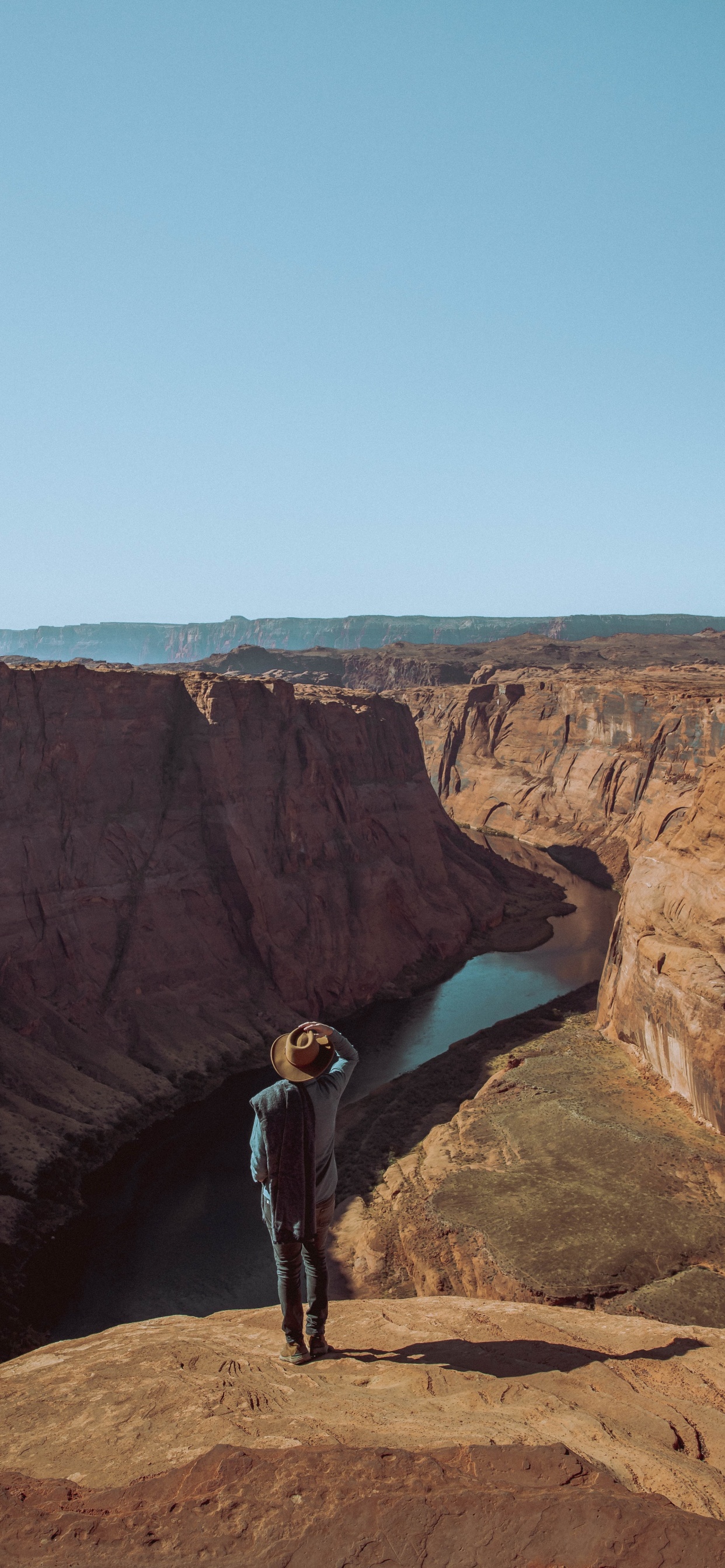 Man in Black Jacket Standing on Brown Rock Formation During Daytime. Wallpaper in 1242x2688 Resolution