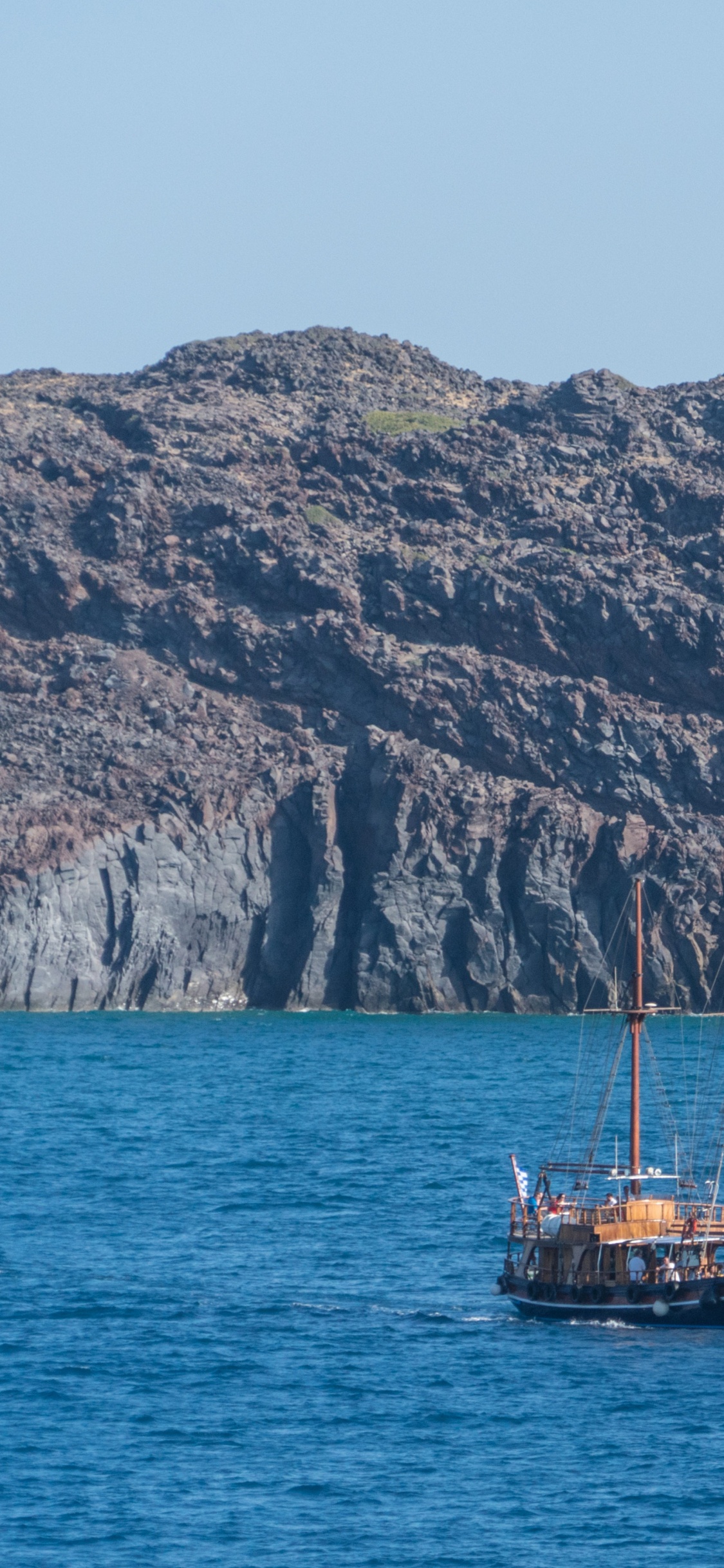 Brown Boat on Blue Sea Near Brown Mountain During Daytime. Wallpaper in 1125x2436 Resolution