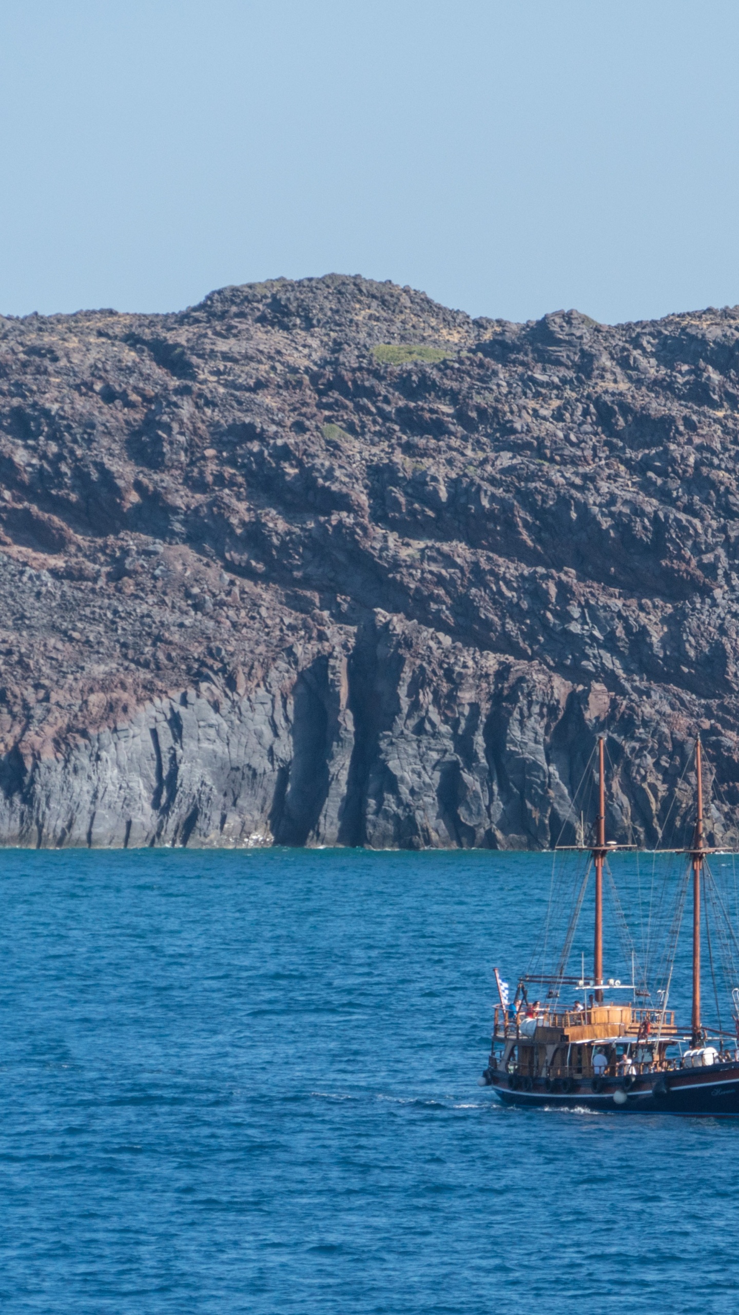 Braunes Boot Auf Blauem Meer in Der Nähe Des Braunen Berges Tagsüber. Wallpaper in 1440x2560 Resolution