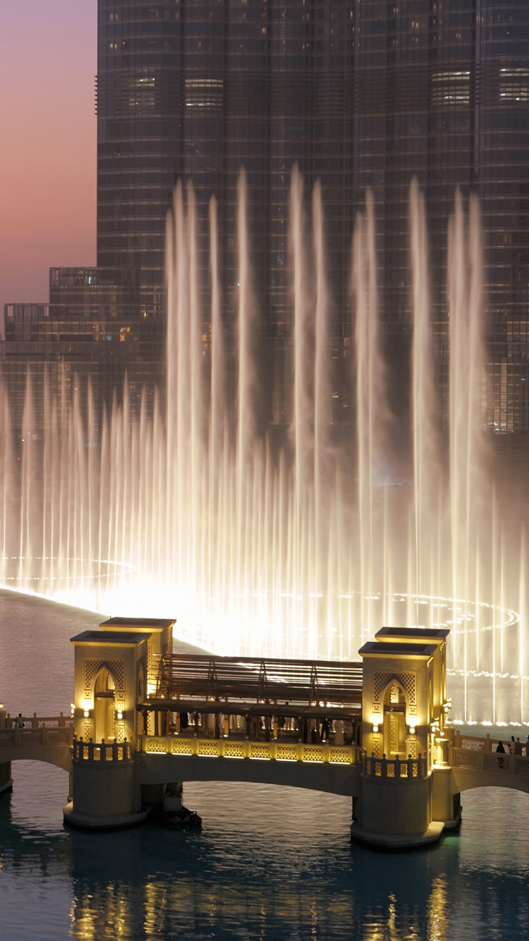 Water Fountain in The Middle of City Buildings During Night Time. Wallpaper in 750x1334 Resolution