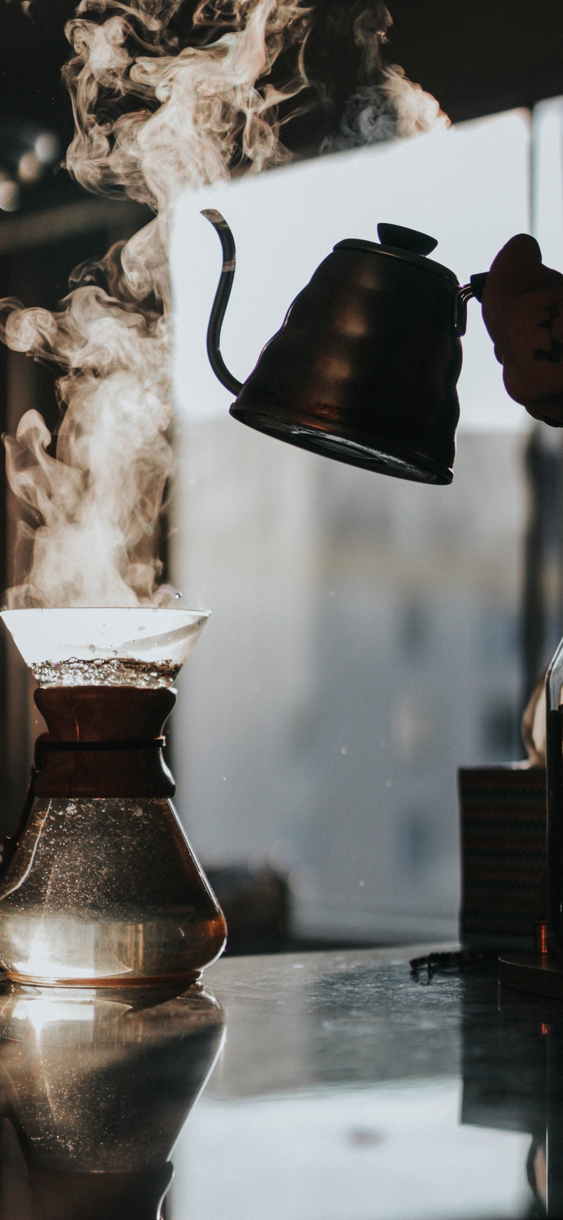 Person Pouring Water From Brown Ceramic Teapot to Clear Glass Pitcher. Wallpaper in 1125x2436 Resolution