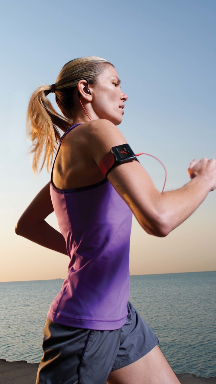 Mujer en Púrpura Tank Top y Pantalones Cortos de Mezclilla Azul de Pie en la Playa Durante el Día. Wallpaper in 720x1280 Resolution
