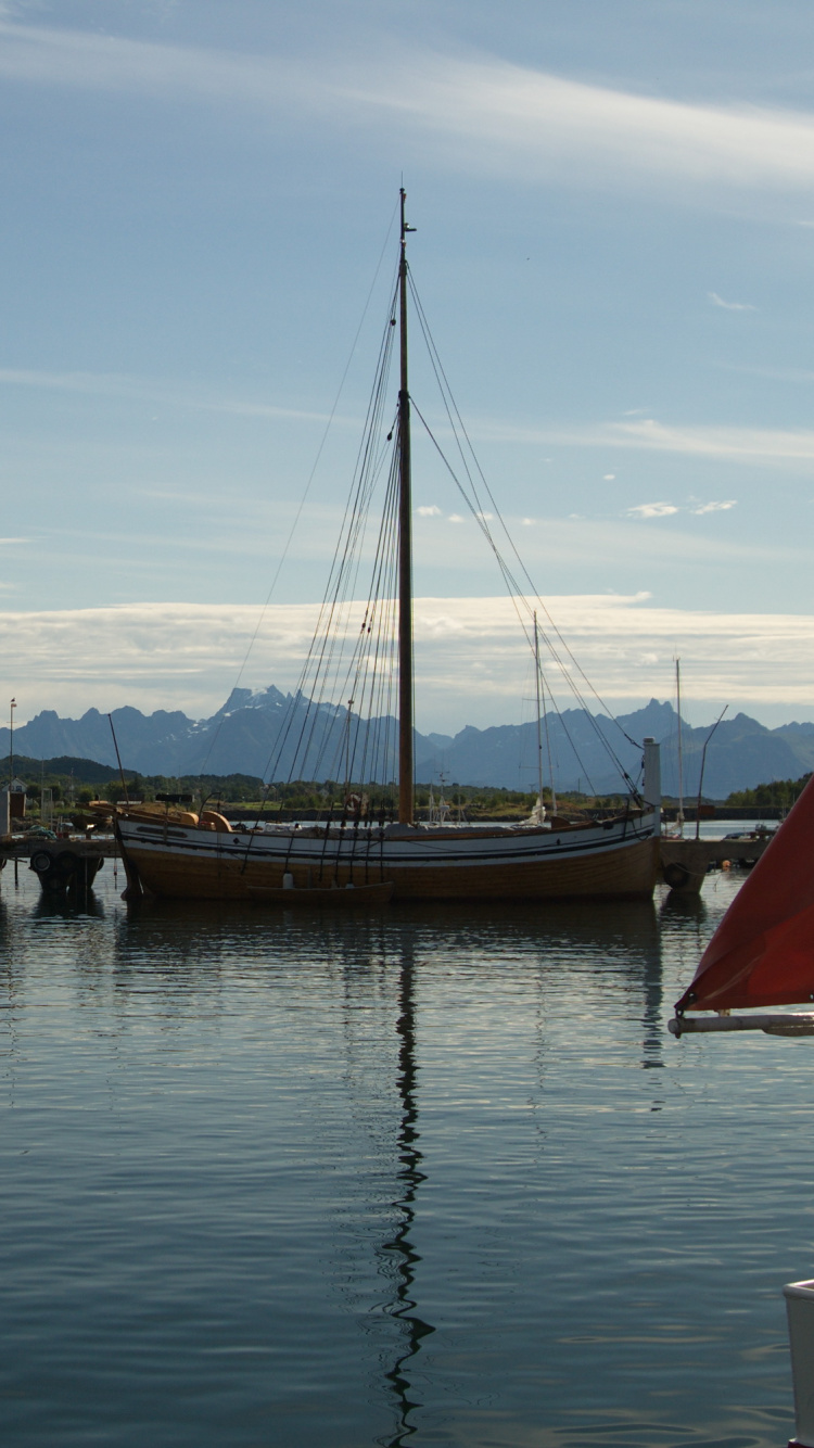 Weißes Und Blaues Boot Auf Dem Wasser in Der Nähe Des Grünen Berges Tagsüber. Wallpaper in 750x1334 Resolution
