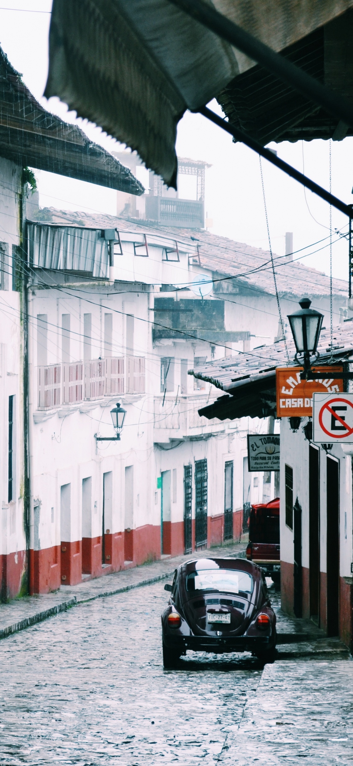 Moto Negra Estacionada Junto al Edificio Blanco y Rojo Durante el Día. Wallpaper in 1125x2436 Resolution