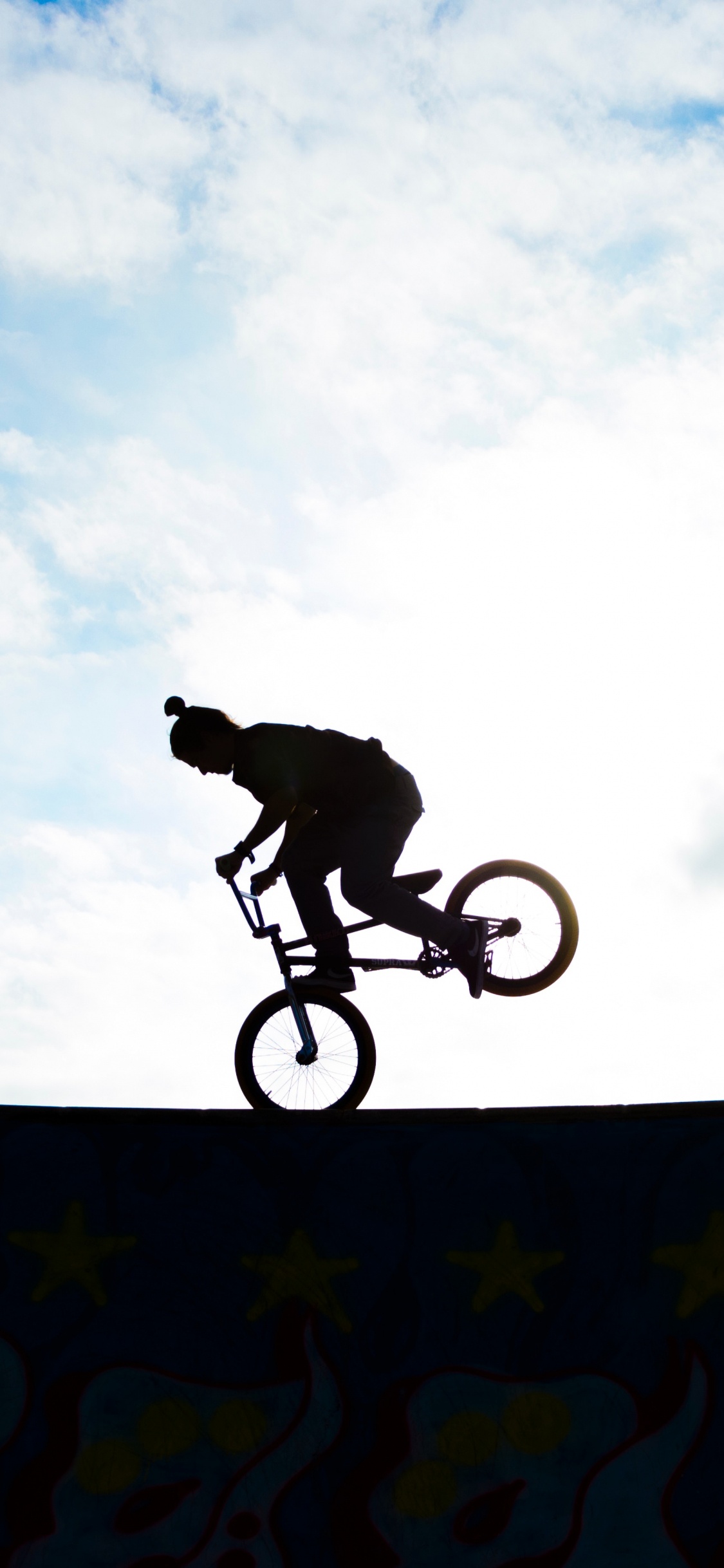 Man Riding Bicycle on Mid Air Under Blue Sky During Daytime. Wallpaper in 1125x2436 Resolution