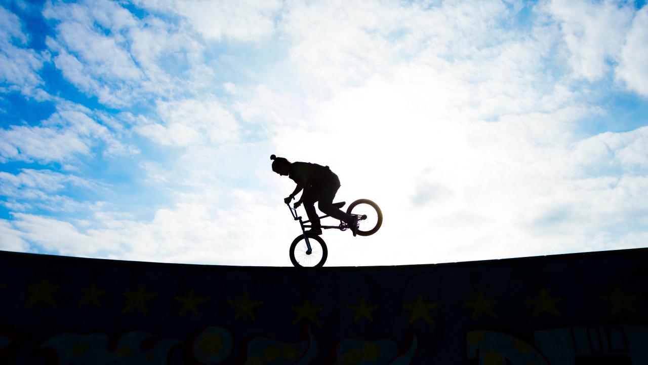Man Riding Bicycle on Mid Air Under Blue Sky During Daytime. Wallpaper in 1280x720 Resolution