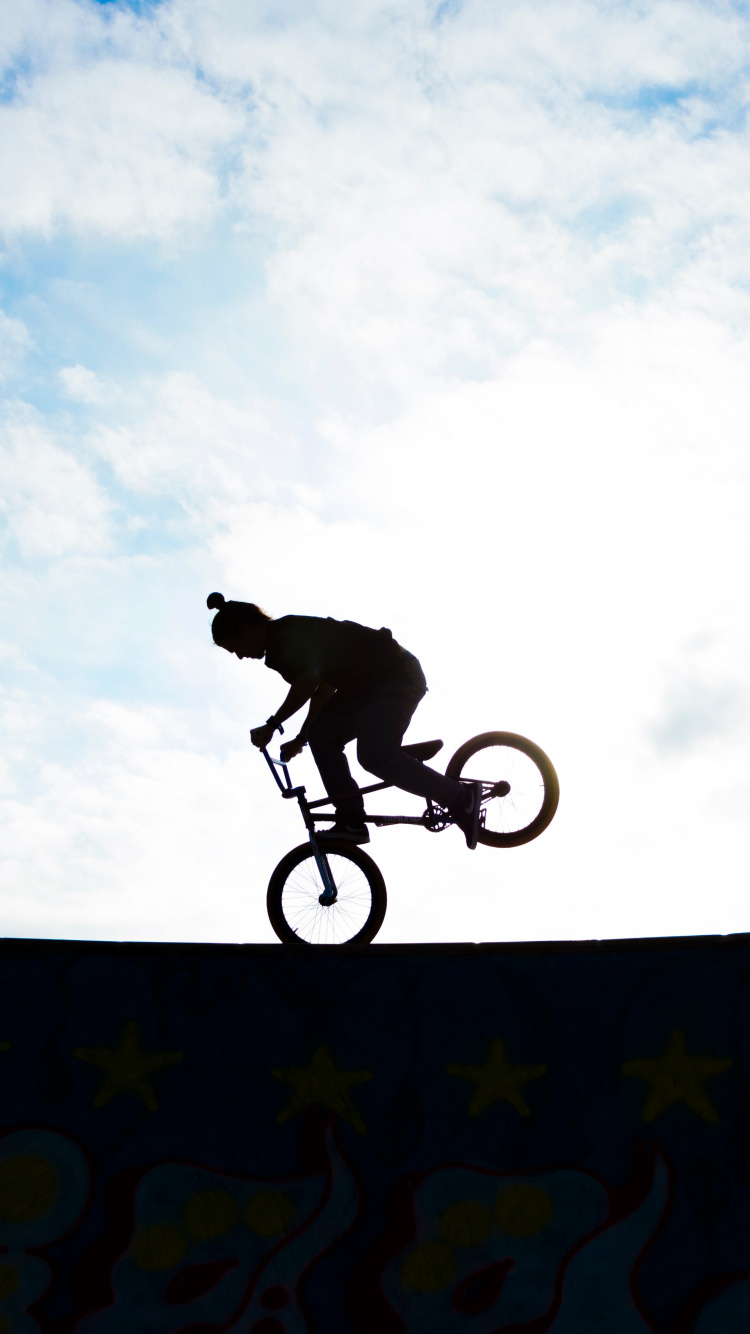 Man Riding Bicycle on Mid Air Sous Ciel Bleu Pendant la Journée. Wallpaper in 750x1334 Resolution