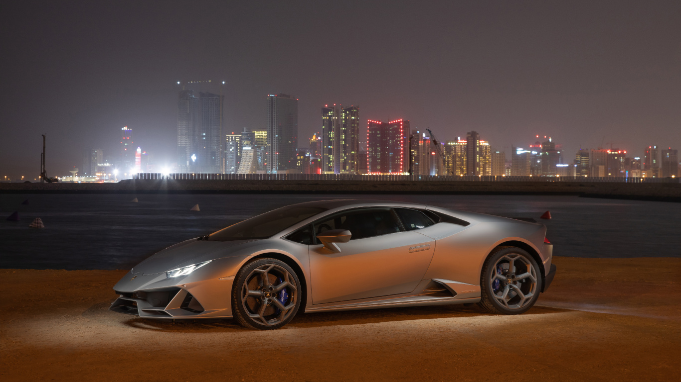 Coupe Blanco Estacionado en el Campo Marrón Cerca de Los Edificios de la Ciudad Durante la Noche. Wallpaper in 1366x768 Resolution