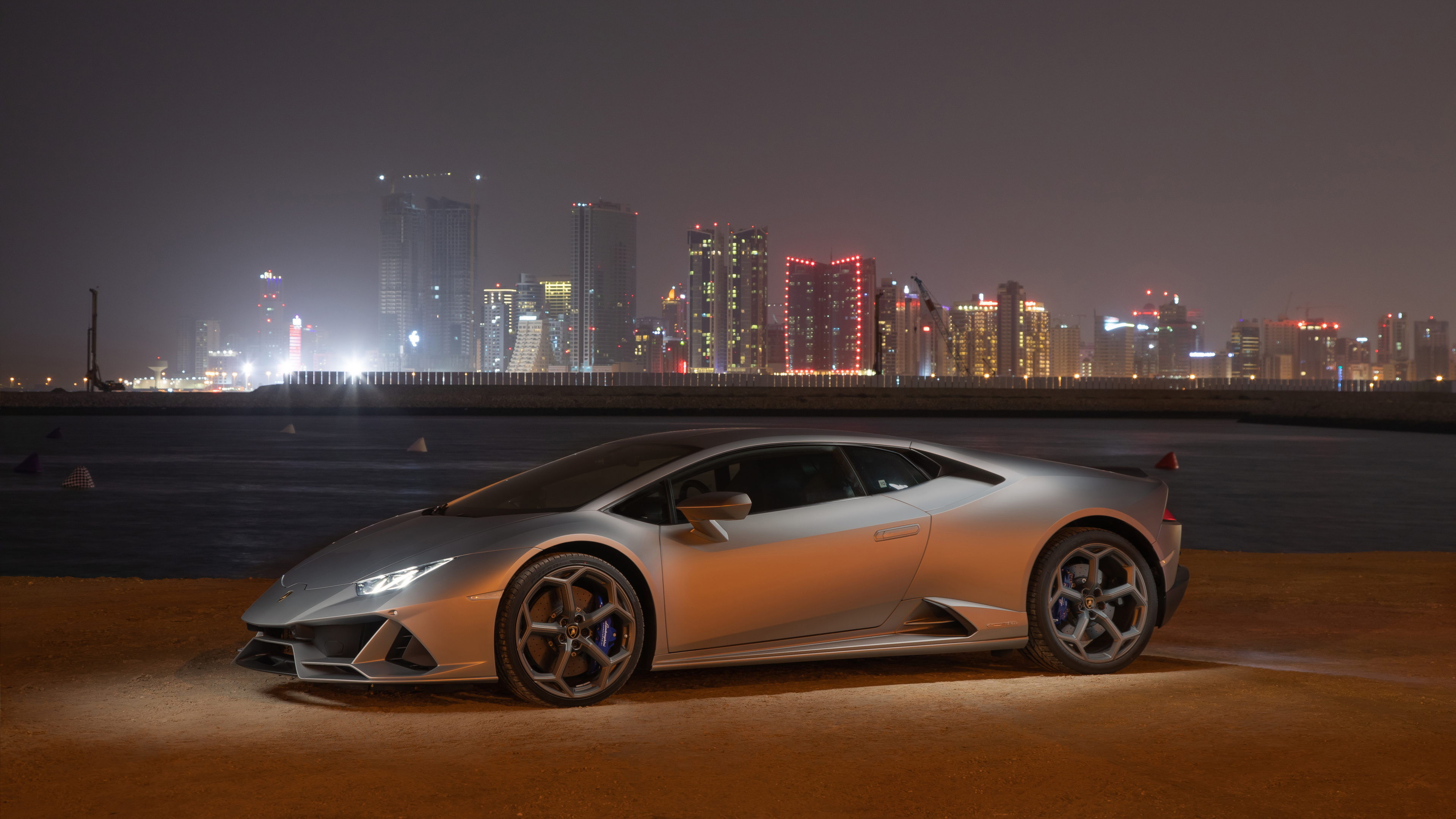 Coupe Blanco Estacionado en el Campo Marrón Cerca de Los Edificios de la Ciudad Durante la Noche. Wallpaper in 3840x2160 Resolution