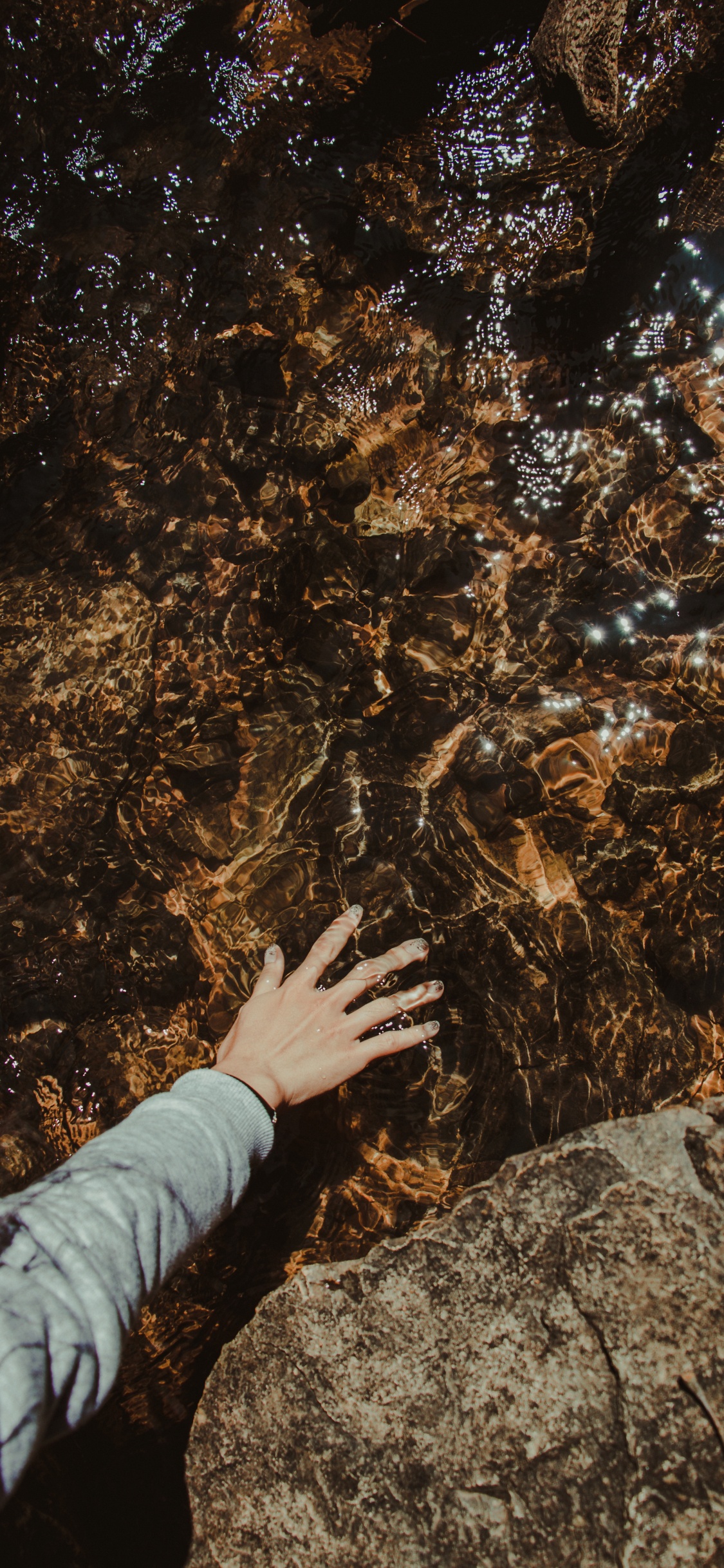 Person in Gray Long Sleeve Shirt Standing on Brown Rock. Wallpaper in 1125x2436 Resolution