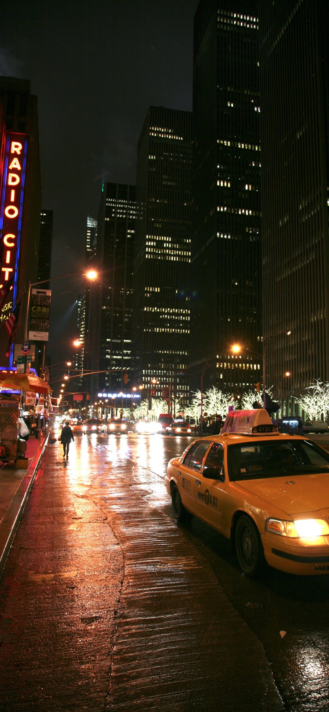 Cars on Road Near High Rise Buildings During Night Time. Wallpaper in 1125x2436 Resolution