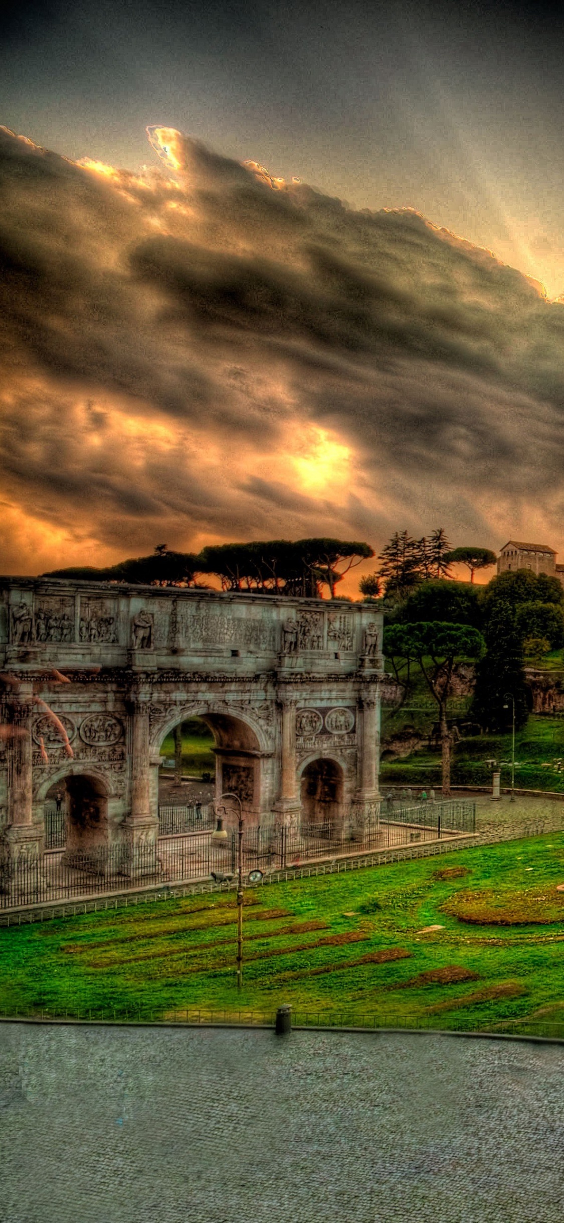 Campo de Hierba Verde Cerca Del Edificio Marrón Bajo el Cielo Nublado. Wallpaper in 1125x2436 Resolution