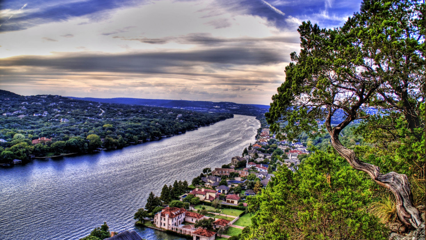 Houses on Green Grass Field Near Body of Water Under Cloudy Sky During Daytime. Wallpaper in 1366x768 Resolution
