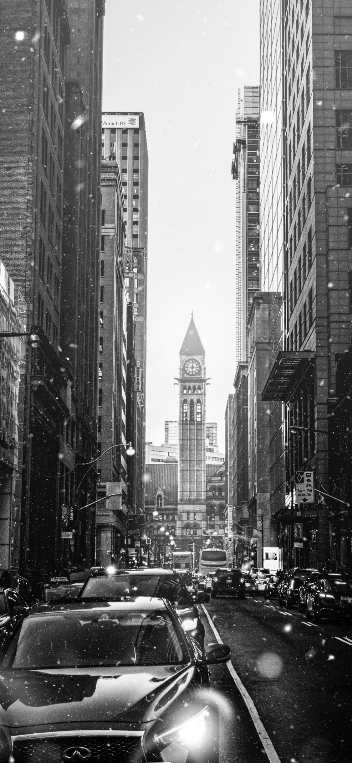 Grayscale Photo of Cars on Road Between High Rise Buildings. Wallpaper in 1125x2436 Resolution