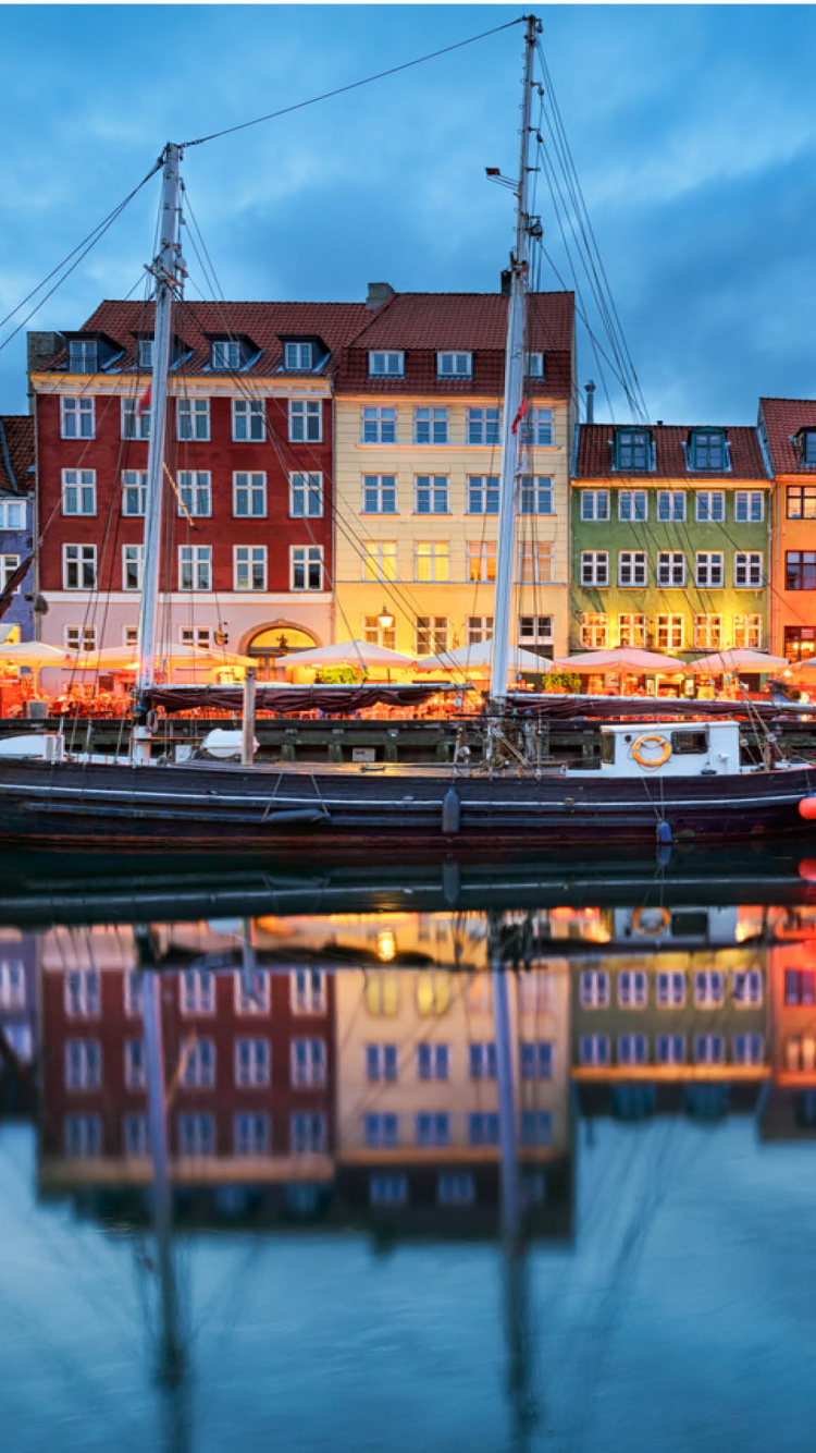 Barco Marrón y Negro en el Río Cerca Del Edificio de Hormigón Marrón Durante el Día. Wallpaper in 750x1334 Resolution