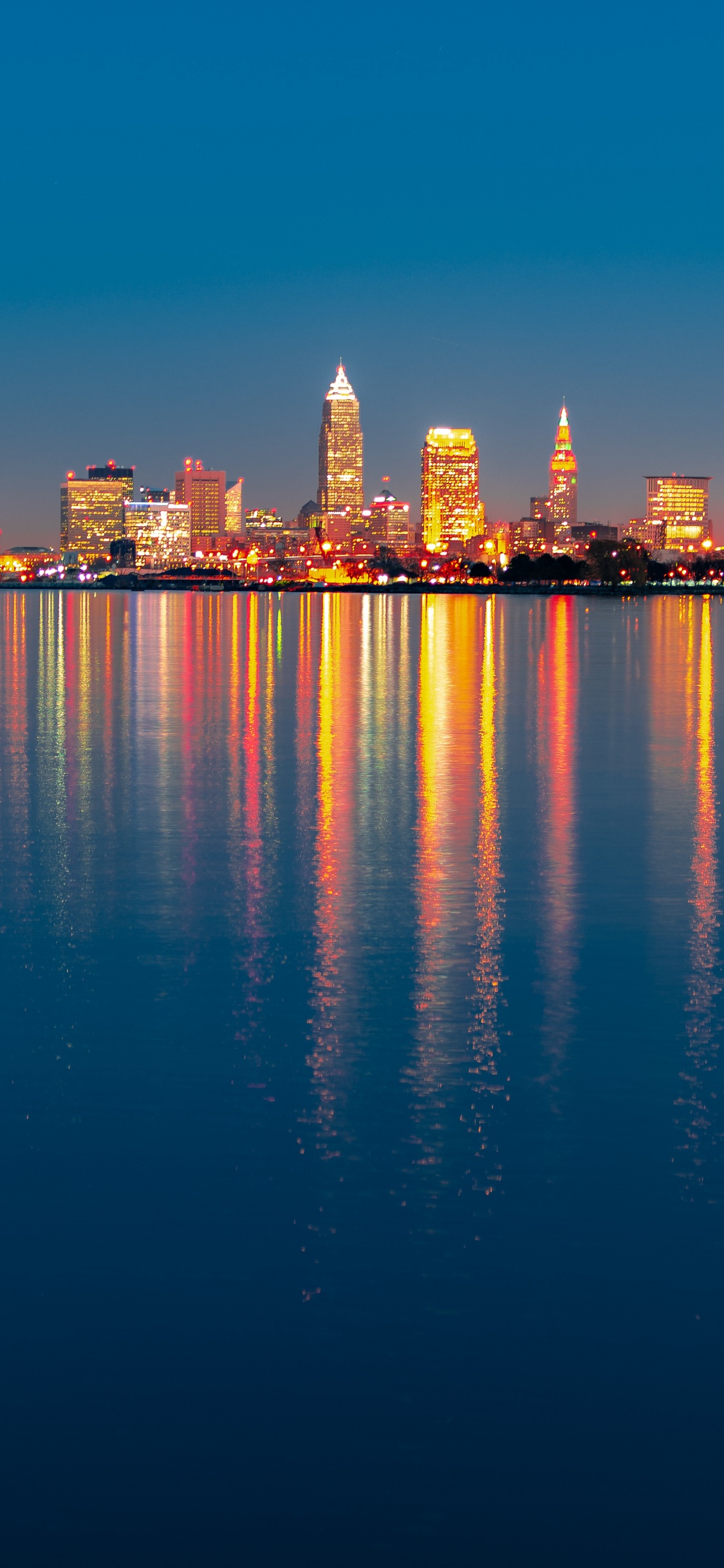 City Skyline Across Body of Water During Night Time. Wallpaper in 1125x2436 Resolution