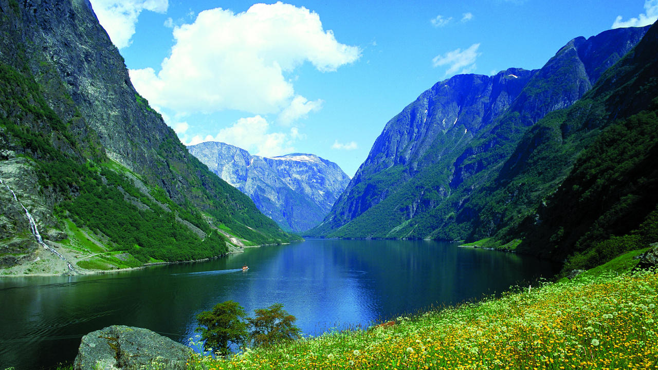 Grüne Wiese in Der Nähe Des Sees Unter Blauem Himmel Tagsüber. Wallpaper in 1280x720 Resolution