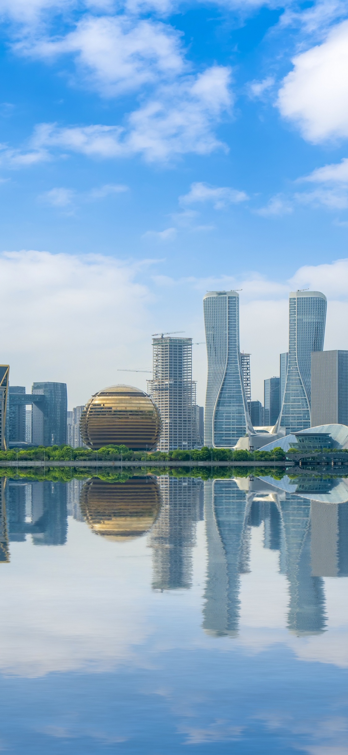 El Horizonte de la Ciudad a Través Del Cuerpo de Agua Bajo el Cielo Nublado Soleado Azul y Blanco Durante el Día. Wallpaper in 1125x2436 Resolution