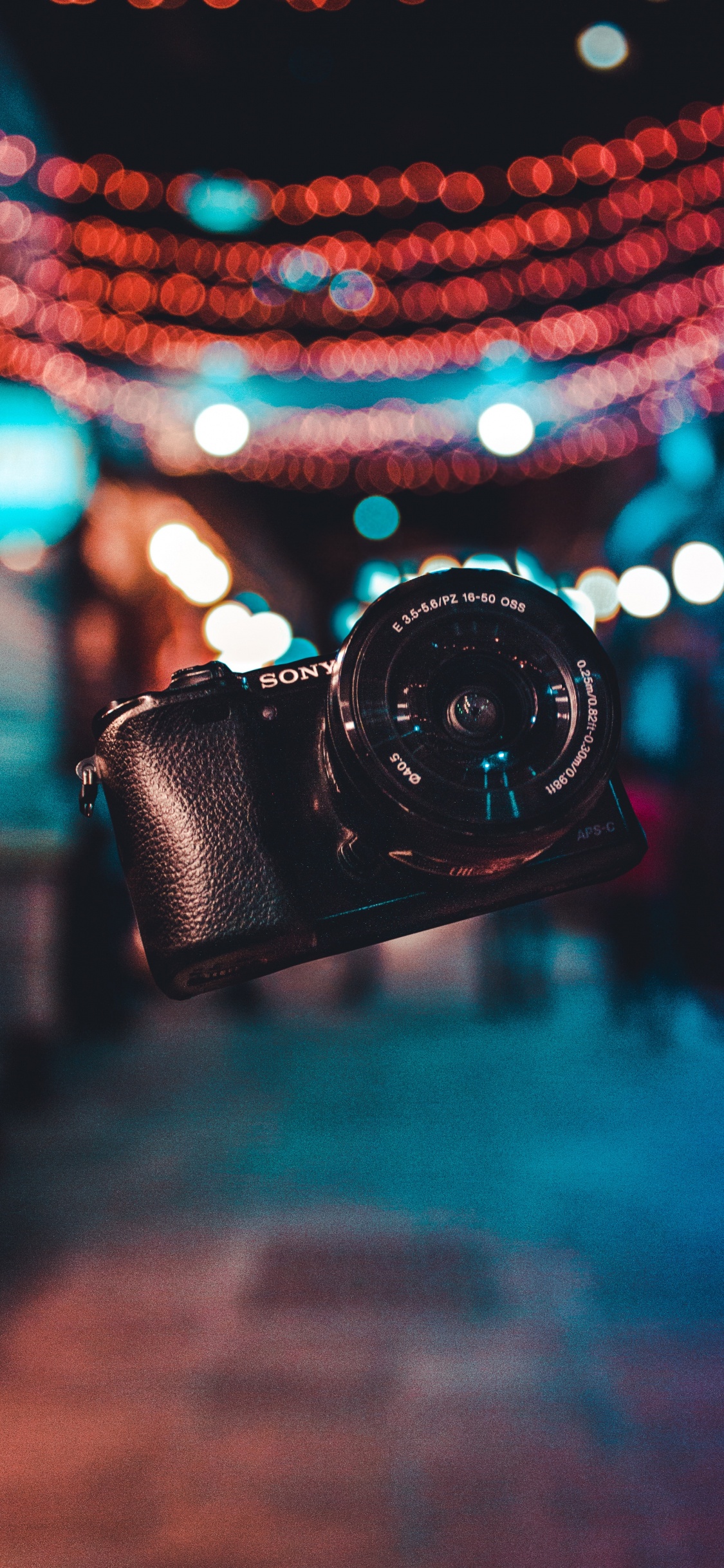 Black Dslr Camera on Blue and White String Lights. Wallpaper in 1125x2436 Resolution