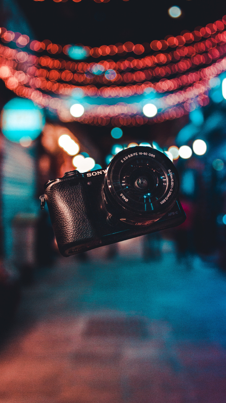 Black Dslr Camera on Blue and White String Lights. Wallpaper in 750x1334 Resolution