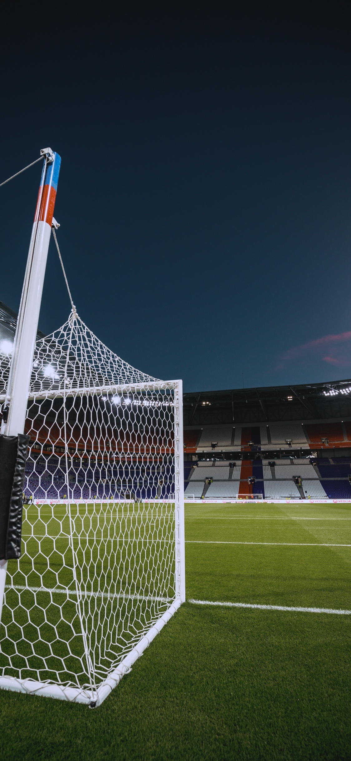 White and Red Flag on Soccer Field During Night Time. Wallpaper in 1125x2436 Resolution