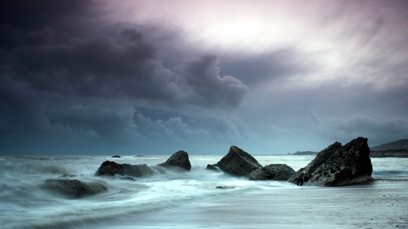 Ocean Waves Crashing on Rocks Under Cloudy Sky. Wallpaper in 1366x768 Resolution