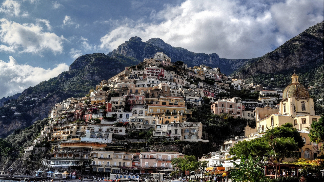 White and Brown Concrete Buildings Near Mountain Under White Clouds During Daytime. Wallpaper in 1280x720 Resolution