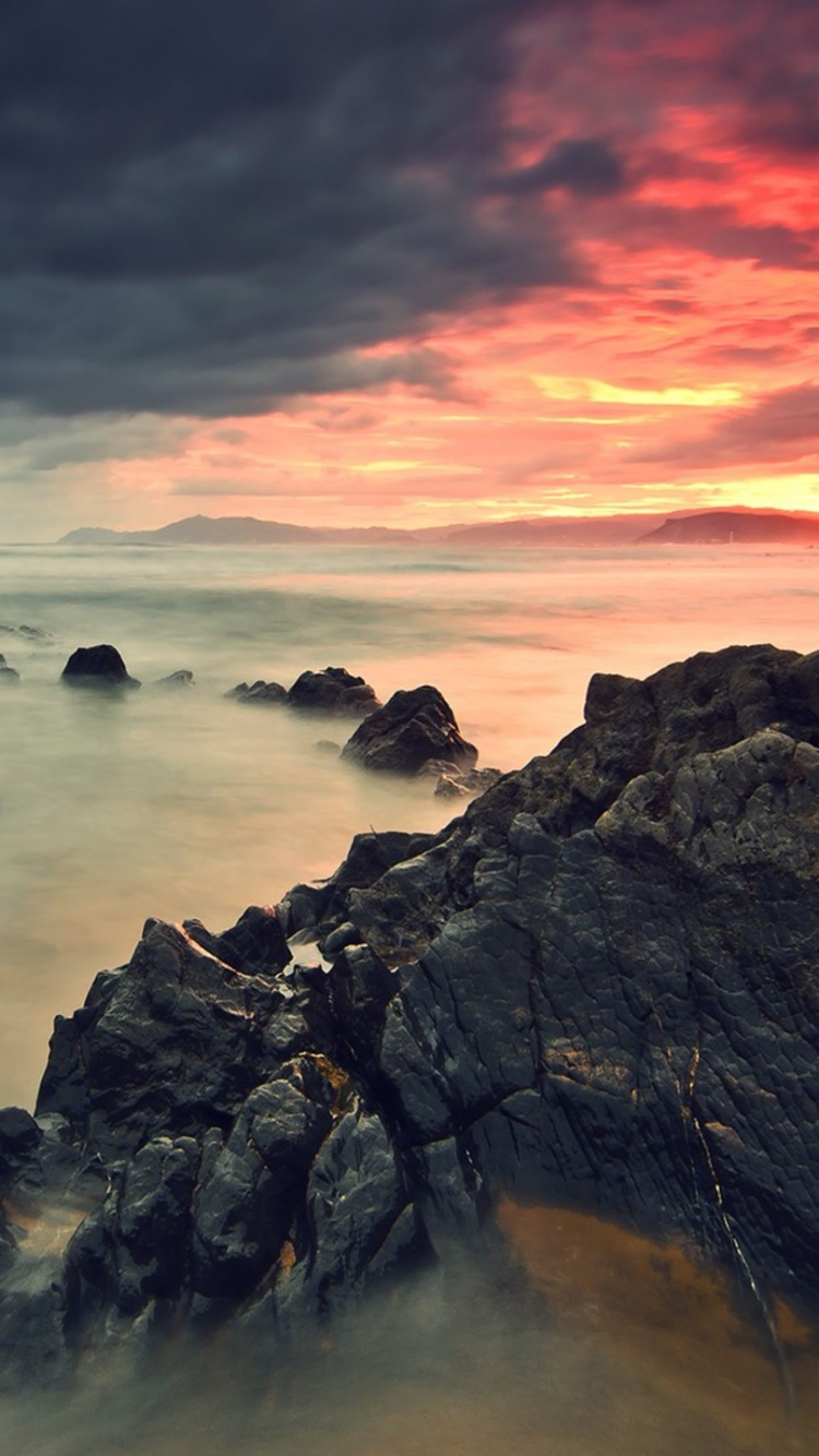 Rocky Shore Under Cloudy Sky During Daytime. Wallpaper in 750x1334 Resolution