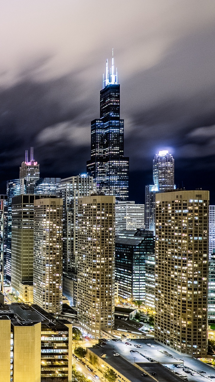 Stadt Mit Hochhäusern Unter Grauen Wolken Während Der Nacht. Wallpaper in 720x1280 Resolution