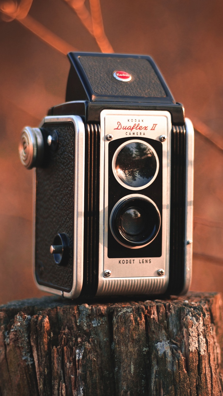 Schwarze Und Silberne Kamera Auf Braunem Holzscheit. Wallpaper in 720x1280 Resolution