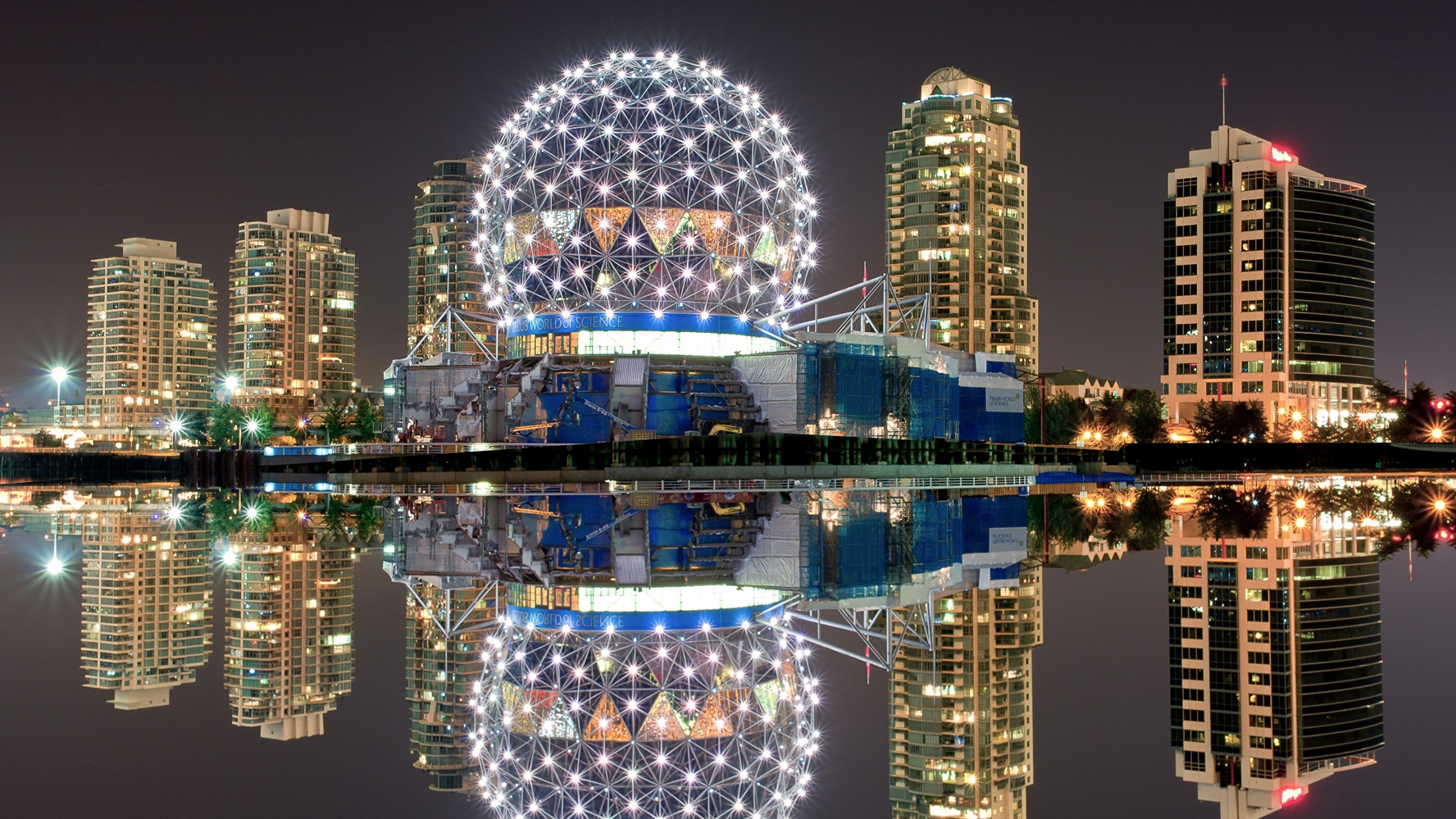 Blue and White Lighted Building Near Body of Water During Night Time. Wallpaper in 2560x1440 Resolution