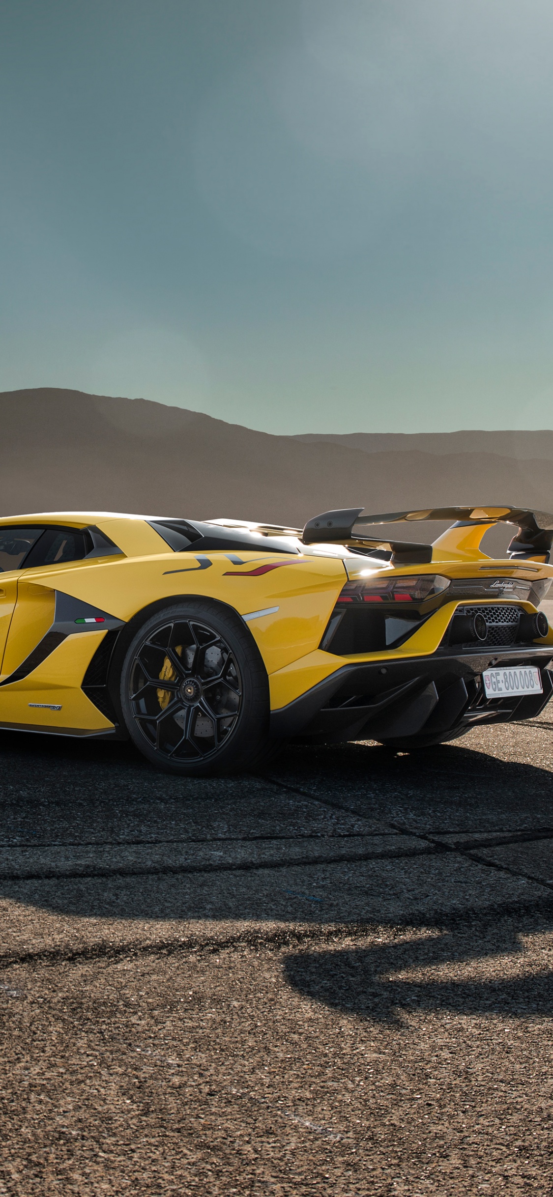 Yellow Porsche 911 on Brown Sand. Wallpaper in 1125x2436 Resolution