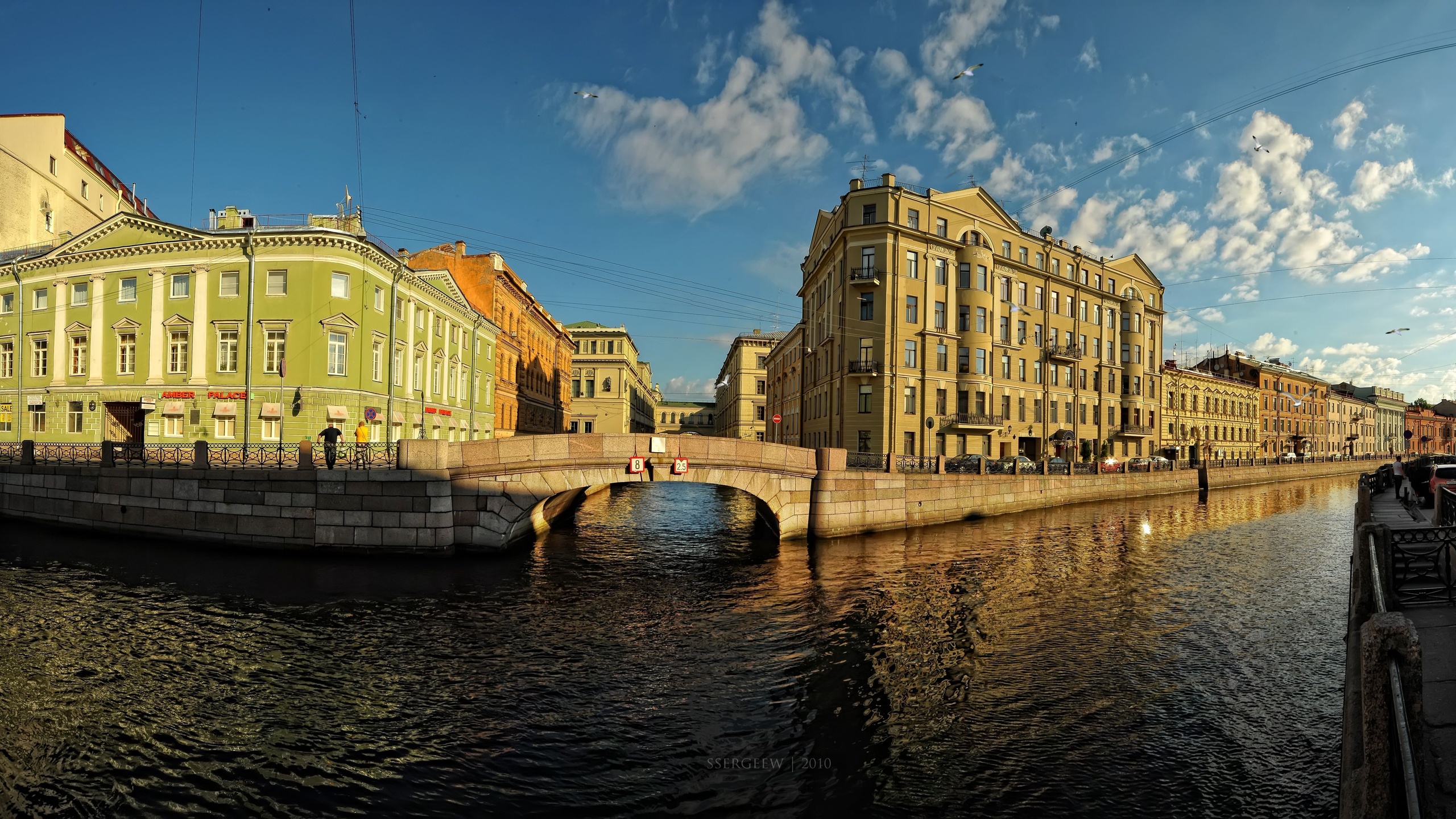 Brown Concrete Building Near River Under Blue Sky During Daytime. Wallpaper in 2560x1440 Resolution