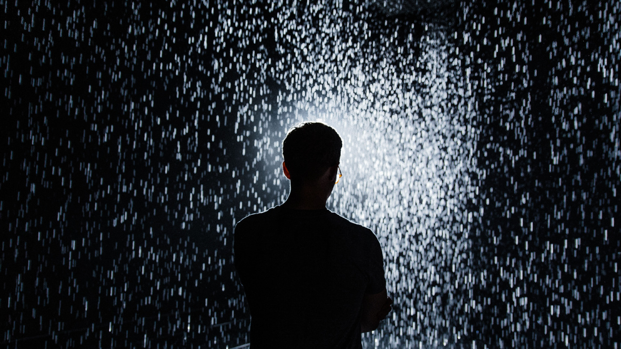 Man in Black Shirt Standing in Front of Water Splash. Wallpaper in 1280x720 Resolution