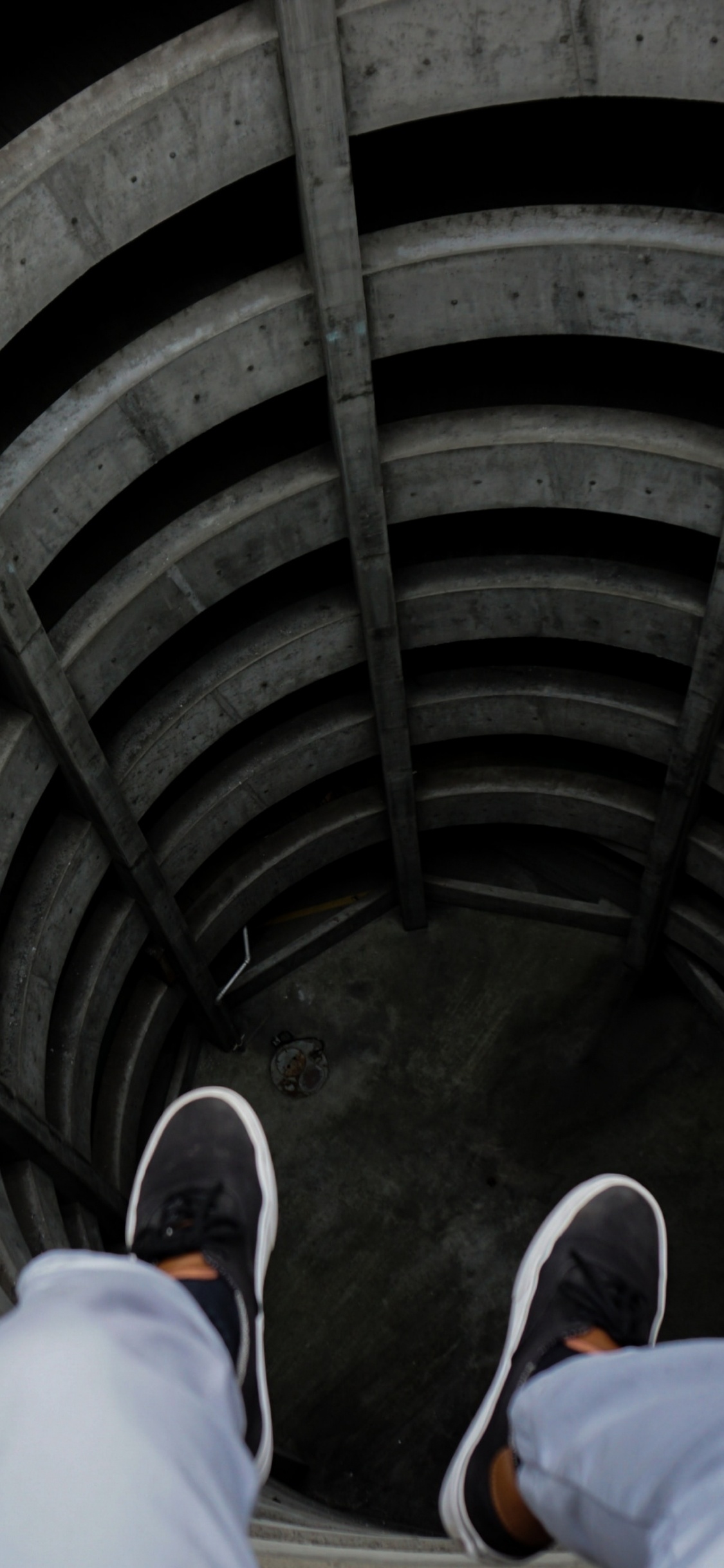 Person in Blue Denim Jeans and Black Shoes Sitting on Tunnel. Wallpaper in 1125x2436 Resolution