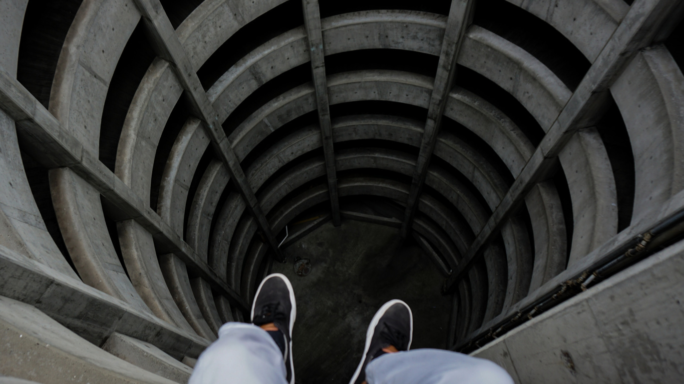 Person in Blue Denim Jeans and Black Shoes Sitting on Tunnel. Wallpaper in 1366x768 Resolution