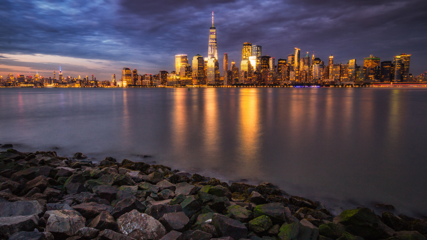 Skyline Der Stadt Über Gewässer Während Der Nacht. Wallpaper in 1366x768 Resolution